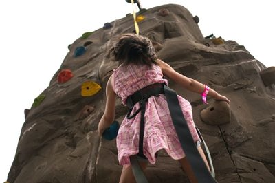 Low angle view of girl climbing on artificial rock