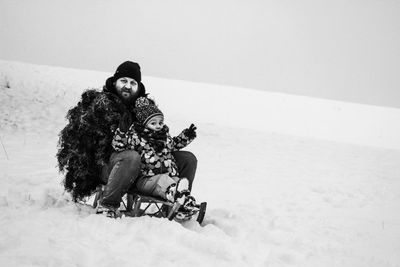 Portrait of young couple sitting on snow covered beach