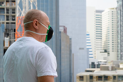 Rear view of man against buildings in city