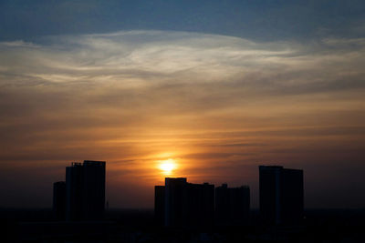 Modern buildings against sky during sunset