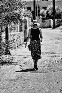 Rear view of woman walking on road in city