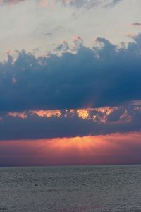 Scenic view of sea against dramatic sky during sunset