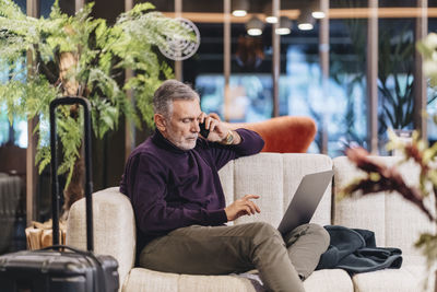 Man using mobile phone while sitting on sofa