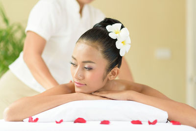 Midsection of masseuse giving massage to young woman relaxing at spa