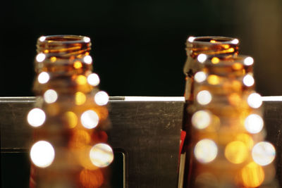 Close-up of candles on empty beer bottles against black background