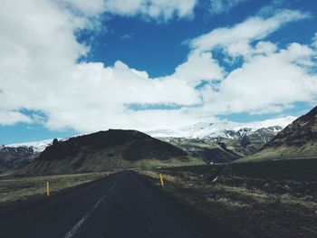 Road leading towards mountains against sky