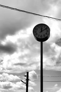 Low angle view of clock on pole against sky