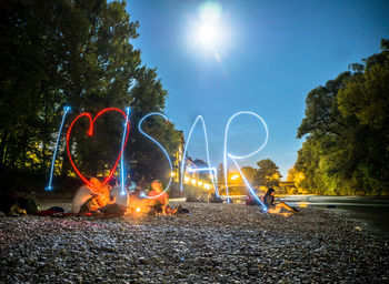 Light painting by river against sky on sunny day