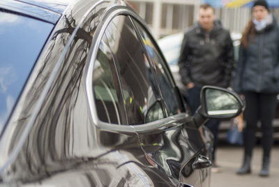 Reflection of man on side-view mirror of car