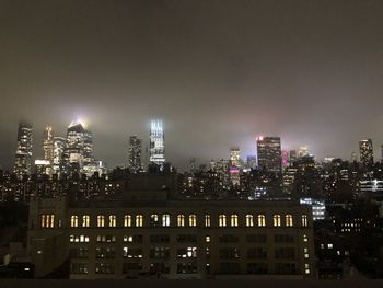 Illuminated buildings in city against sky at night