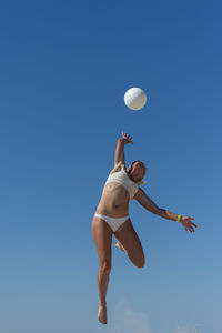 Woman jumping against clear blue sky