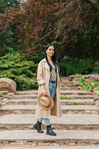 Portrait of young woman standing against rock