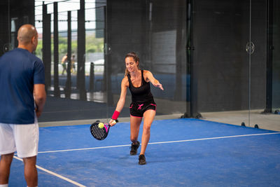 Monitor teaching padel class to woman, his student - trainer teaches young girl how to play padel 