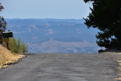 Scenic view of road by mountains against clear sky