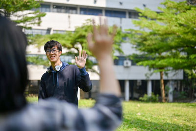 Side view of young man standing against trees