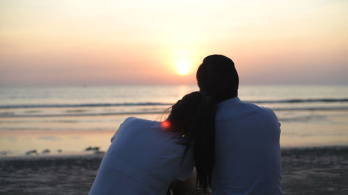 Rear view of couple on beach during sunset