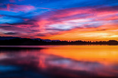 Scenic view of lake against dramatic sky during sunset