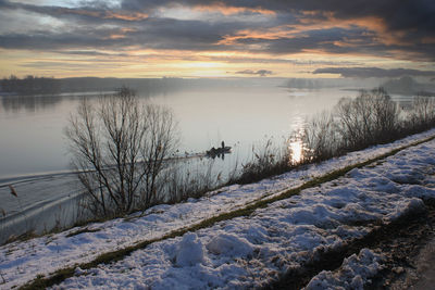 Sporty fisherman in boat on the river in winter season