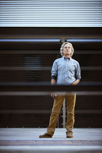 Mature man standing on floor with hand in pocket