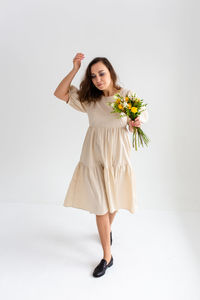 Portrait of young woman standing against white background