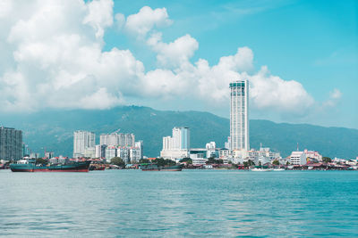 Sea by buildings against sky in city