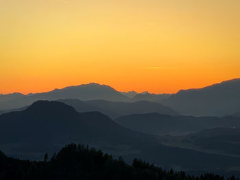 Scenic view of silhouette mountains against orange sky