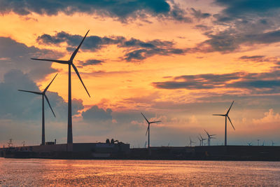 Wind turbines in antwerp port on sunset. belgium