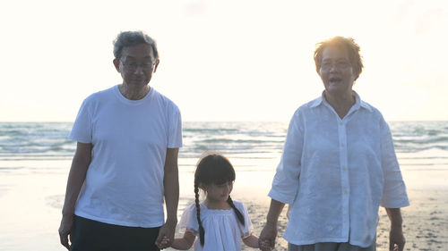 Rear view of friends on beach against sky