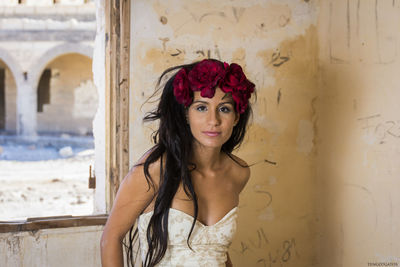 Portrait of beautiful young woman standing against wall