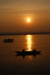 Silhouette boat in sea against sky during sunset