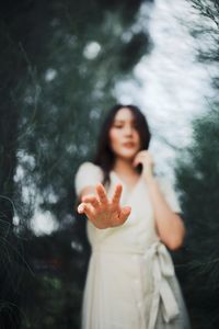 Young woman looking at camera while standing against trees