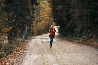 Full length of woman standing on road amidst trees