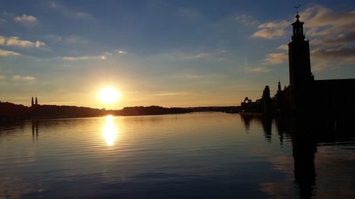Scenic view of calm lake against cloudy sky during sunset