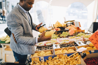 Mature man buying squash vegetables from market stall