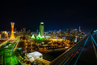 Illuminated modern buildings in city against sky at night