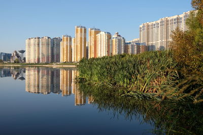 Reflection of buildings on lake against sky in city