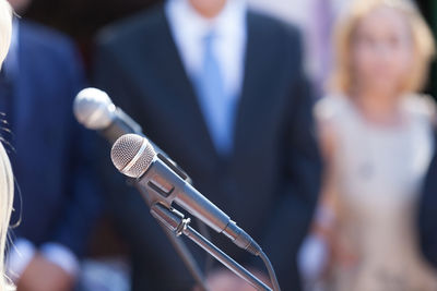 Close-up of microphones with people standing in background