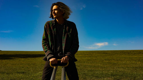 Young man sitting on see-saw against sky