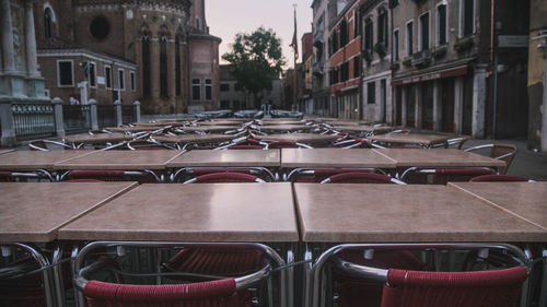 Empty chairs in street against buildings in city