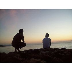 Woman standing on shore at sunset