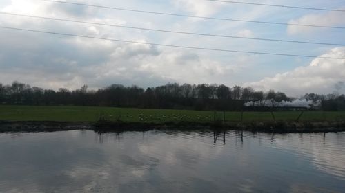 Scenic view of calm lake against cloudy sky