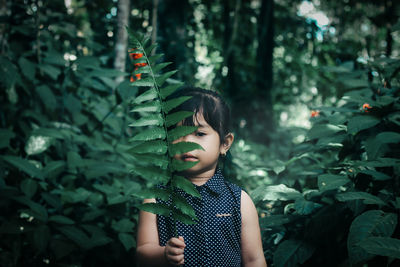 Boy standing by plants in forest