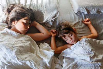 Upper view on two children sleeping on parents bed