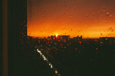 Illuminated cityscape against sky during sunset