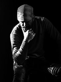 Thoughtful man sitting against black background