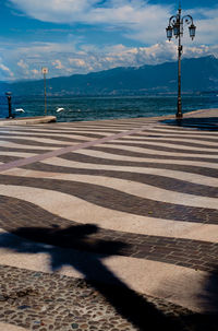 Striped pedestrian zone by sea against sky