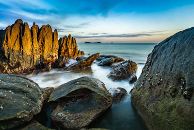 Rock formations in sea against sky during sunset