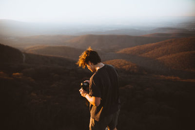 Man standing on mountain landscape against sky