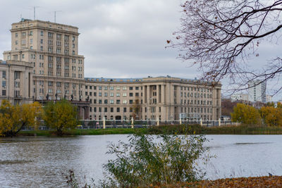 Buildings by lake against sky in city