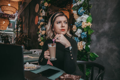 Portrait of woman drinking glass on table